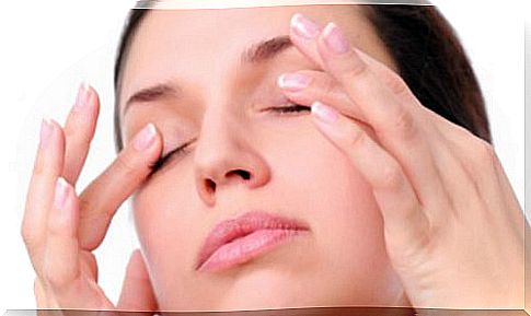 A woman touching her eyelids with her fingertips