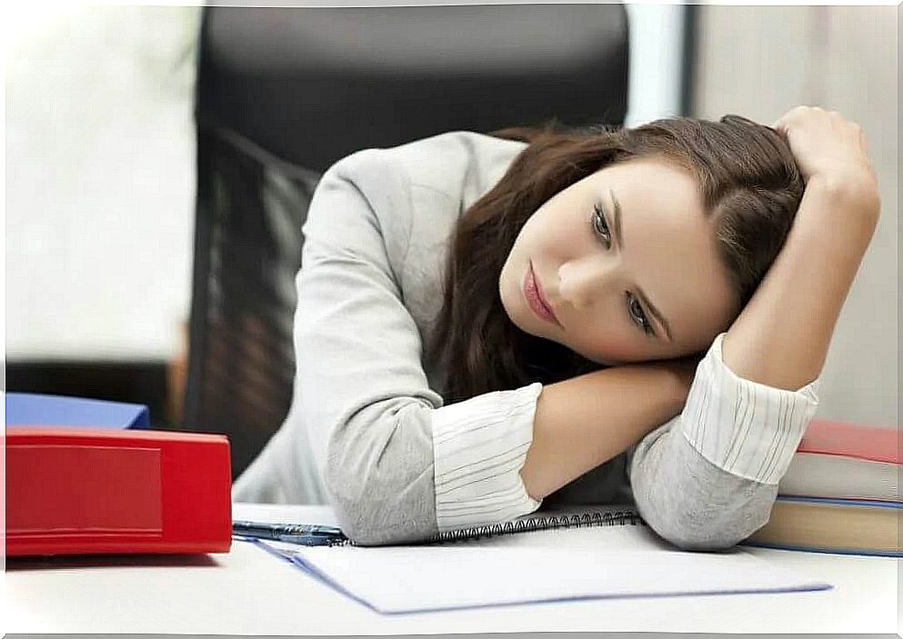 A sad woman is leaning against the desk